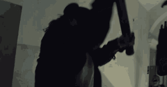 a person is holding a bat in a dark room .