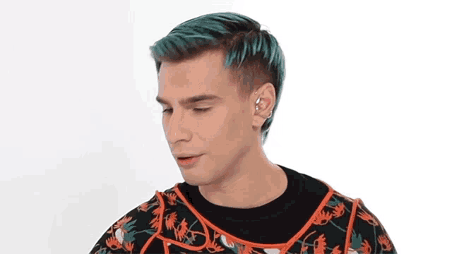 a man with green hair is wearing a black and orange sweater