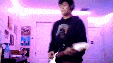 a man wearing headphones is playing an electric guitar in a room .