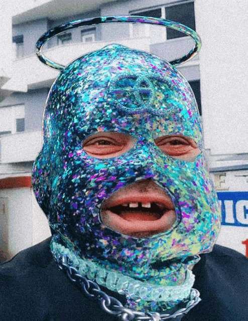 a man wearing a colorful mask has a chain around his neck and a halo around his head