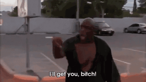 a man smoking a cigarette in a parking lot and saying i 'll get you bitch