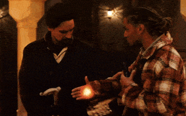 two men are standing next to each other and one has a glowing object in his hand
