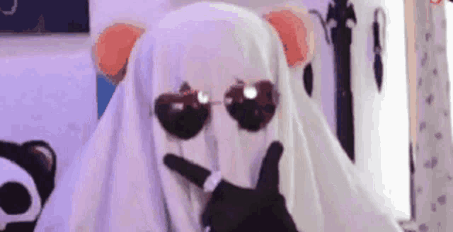 a ghost wearing sunglasses and a panda mask is making a face .