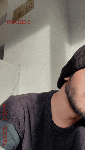 a man with a beard wearing a black sweater and a black hat