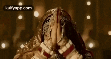 a bride is praying with her hands folded in front of her face .