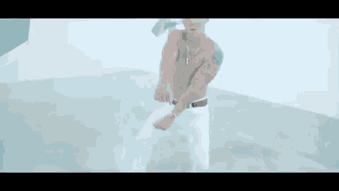 a shirtless man in a baseball cap is dancing in a white room .