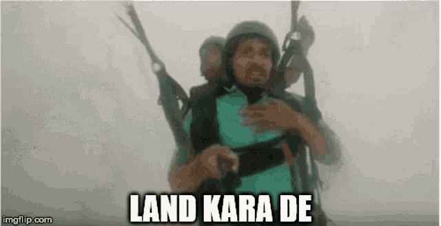 a man is flying a parachute with another man on his back and the words `` land kara de '' written above him .