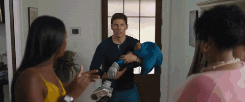 a man is holding a baby in his arms while a woman talks to him in a living room .