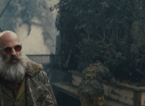 a bald man with a beard is talking to another man