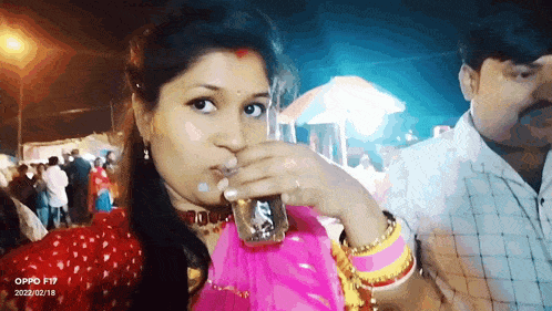 a woman drinking from a glass with the word oppo f19 on the bottom
