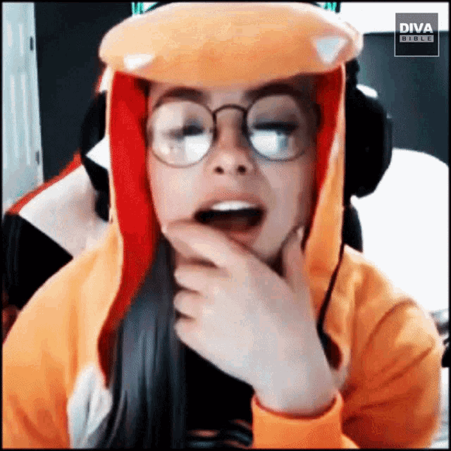 a woman wearing glasses and a diva hoodie holds her hand to her chin