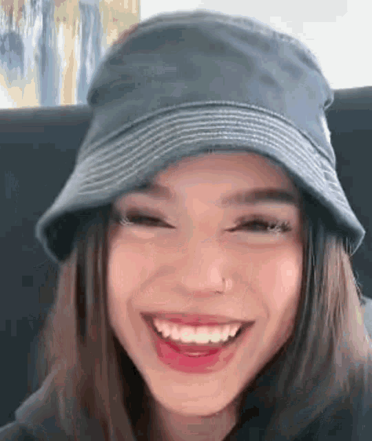 a woman wearing a bucket hat is smiling and making a face .