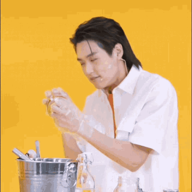 a man in a white shirt is pouring something into a metal bucket