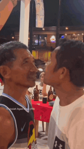 a man wearing a nike jersey is kissing another man