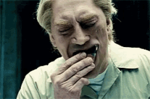a man in a tan shirt is eating something with his hand