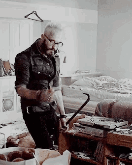 a man with glasses and a beard is holding a cane in a room