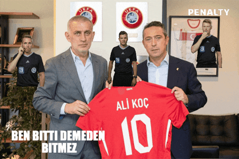 a man in a suit holds a red shirt with the number 10 on it