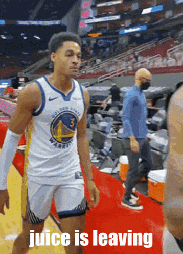a man in a golden state warriors jersey stands on a red carpet