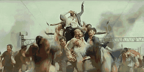 a group of zombies are running through a crowd of people in a city .
