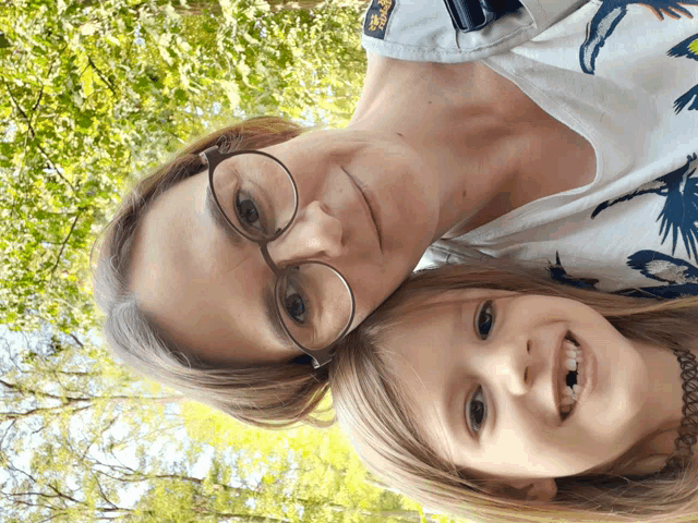 a woman wearing glasses and a child wearing a shirt that has a bird on it