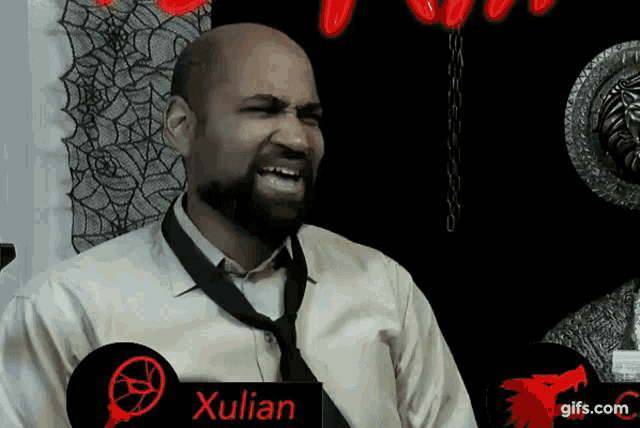 a bald man with a beard is wearing a black tie and a sign that says xulian on it