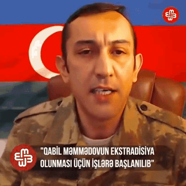 a man in a military uniform is sitting in front of an azerbaijan flag .