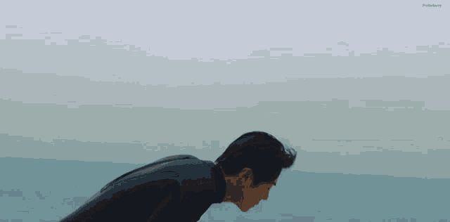 a man in a wetsuit is bending over in the ocean