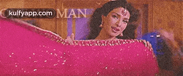 a woman in a pink dress is smiling and holding a pink cloth .