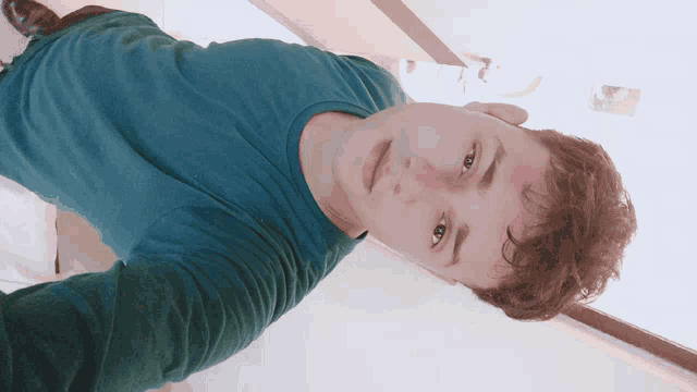 a young man in a blue shirt is taking a picture of himself