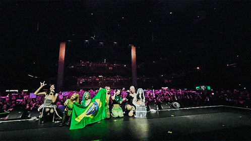 a group of women holding a brazilian flag on a stage in front of a crowd