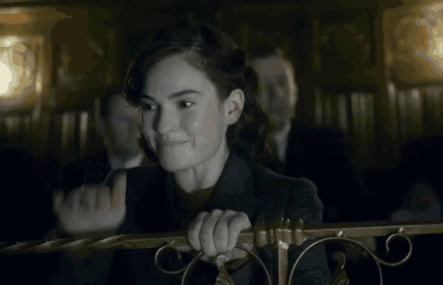 a woman in a suit is holding onto a railing in a dark room .
