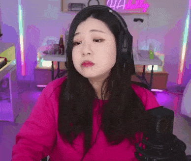 a woman wearing headphones is sitting in front of a microphone and making a funny face .