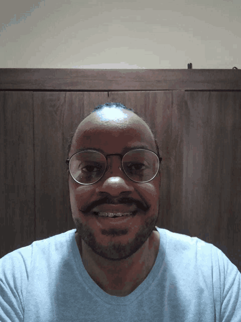 a man with glasses and braces on his teeth smiles
