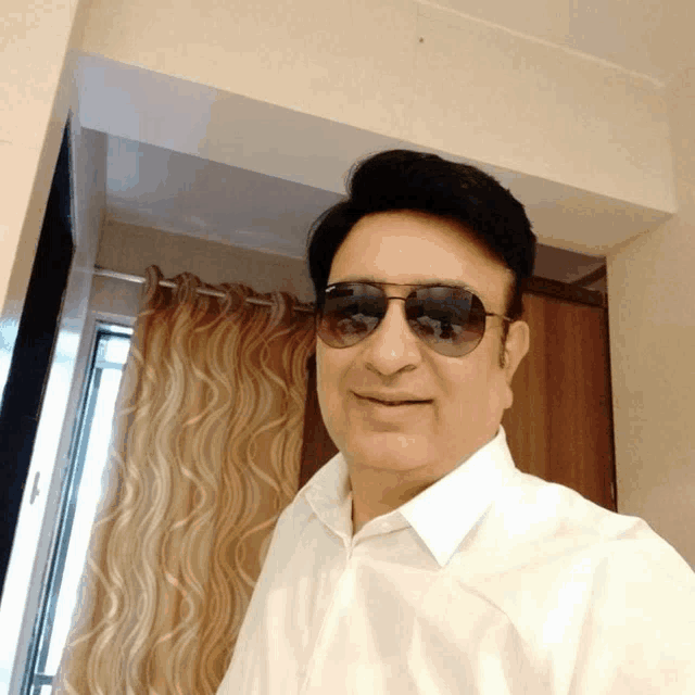 a man wearing sunglasses and a white shirt takes a selfie
