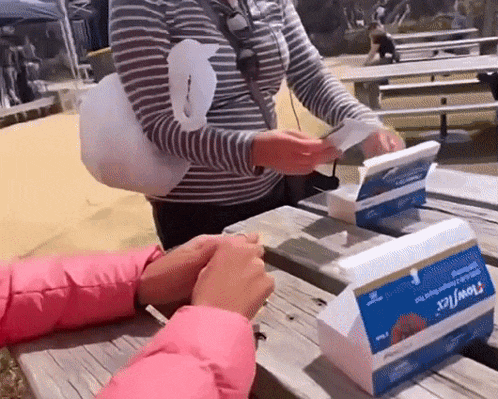 a woman is sitting at a picnic table with a box of tissues on it .