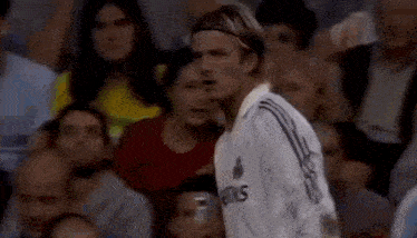 a man in a soccer uniform is standing in front of a crowd of people .