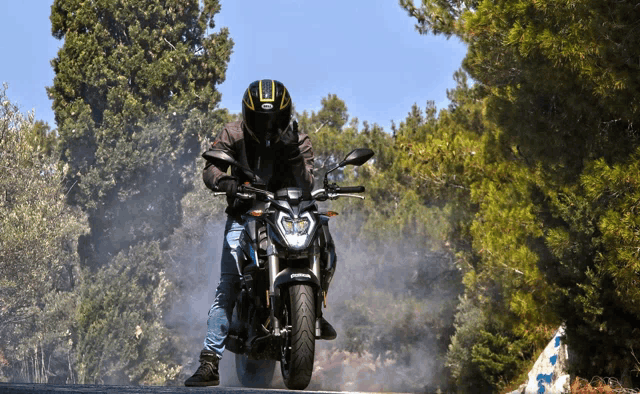 a man wearing a black and yellow helmet rides a motorcycle