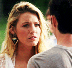 a woman wearing earrings looks at a man in a gray shirt