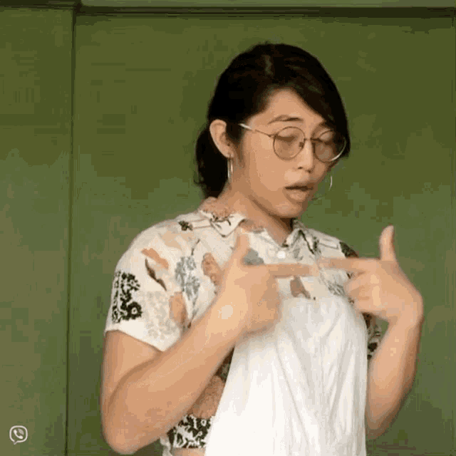 a woman wearing glasses and a white shirt is pointing at something
