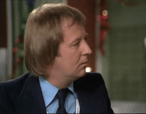 a man in a suit and tie has a very long haircut