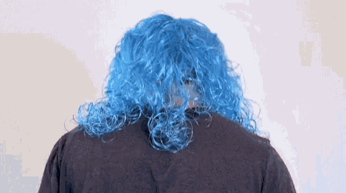 a man wearing a blue wig and glasses is dancing .