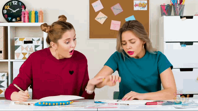 two girls are sitting at a desk with a clock on the wall that says 12 on it