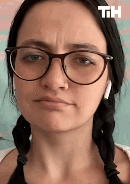 a woman wearing glasses and ear buds with the letters th behind her