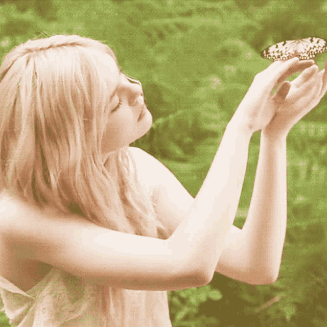 a woman is holding a butterfly in her hands with a green background