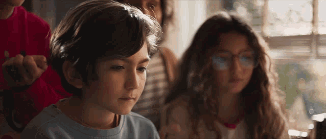 a boy in a blue shirt is looking at something