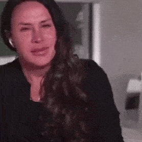 a woman with long hair is crying while wearing headphones and a black shirt .