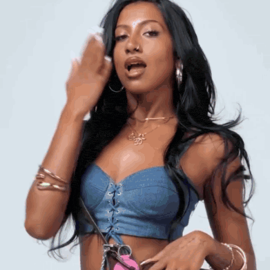 a woman wearing a denim crop top with a necklace that says ' i love you ' on it