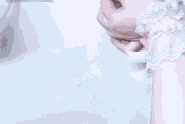 a woman 's hand is wearing a white lace wristband with a pink ribbon .