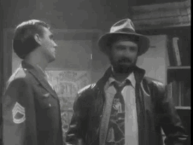 a man in a military uniform is talking to another man in a hat with correct me if i 'm wrong written in green