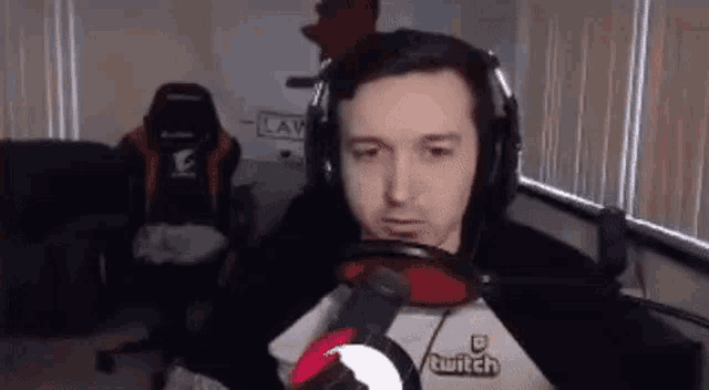 a man wearing headphones and a microphone is sitting in front of a window in a room .